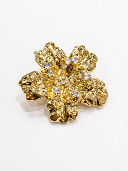 Gold flower-shaped earring with embedded crystals on a white background