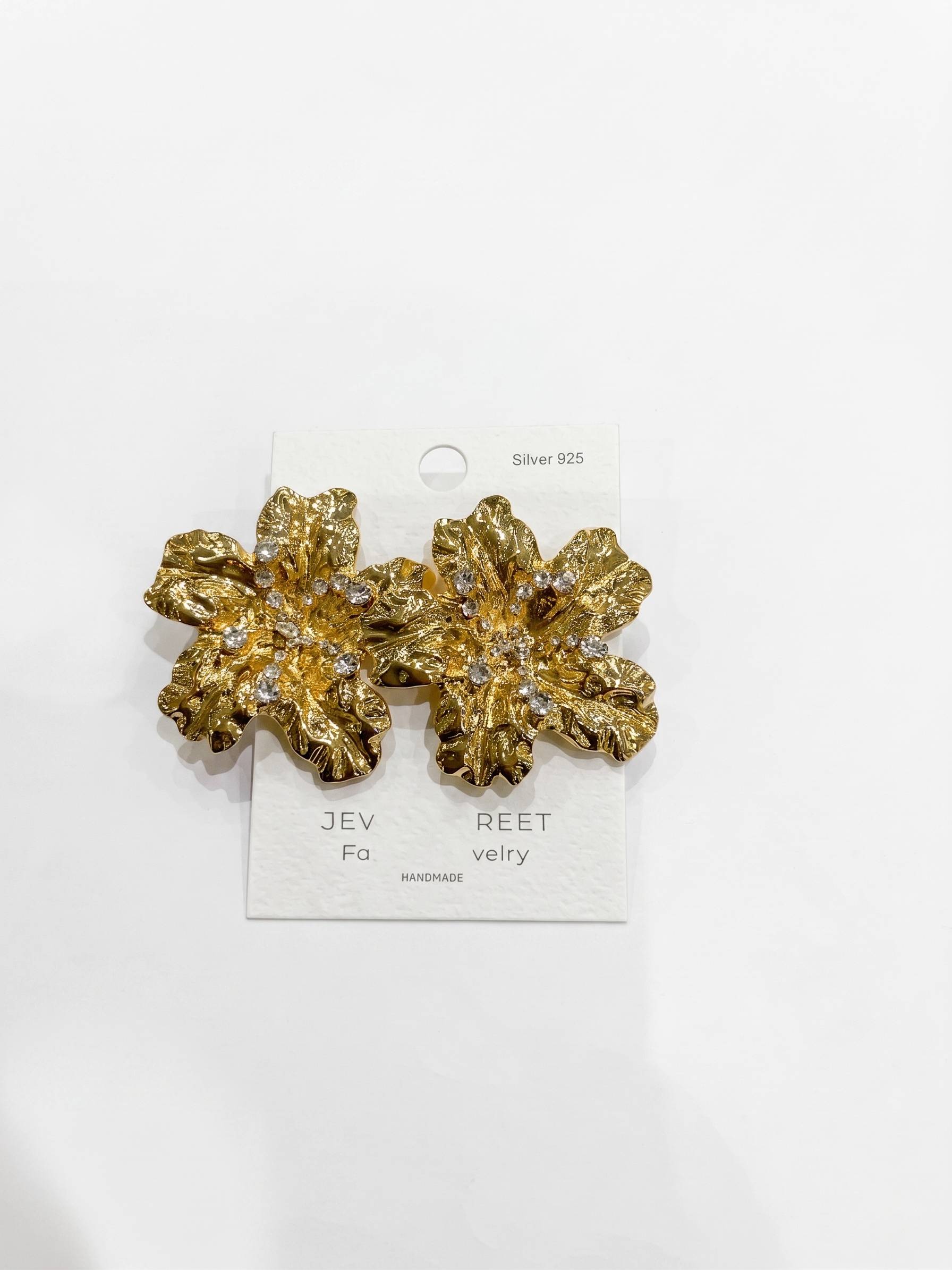 Gold floral earrings on a white card with brand name.