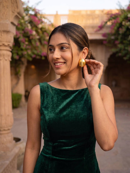 Woman in a green dress with gold earrings outdoors