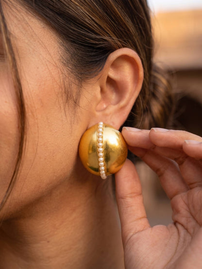 Gold earring with pearl detail being worn by a person