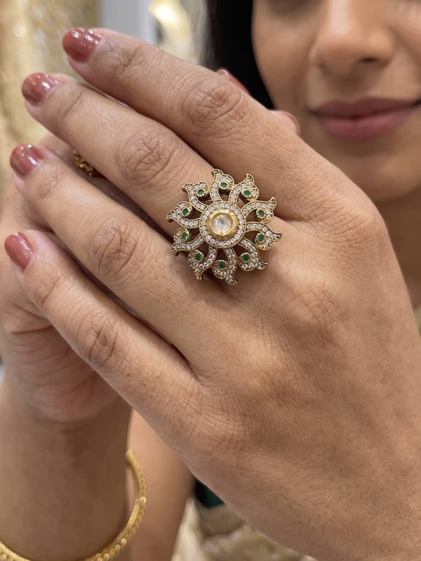 Close-up of a hand wearing an ornate ring with gemstones.