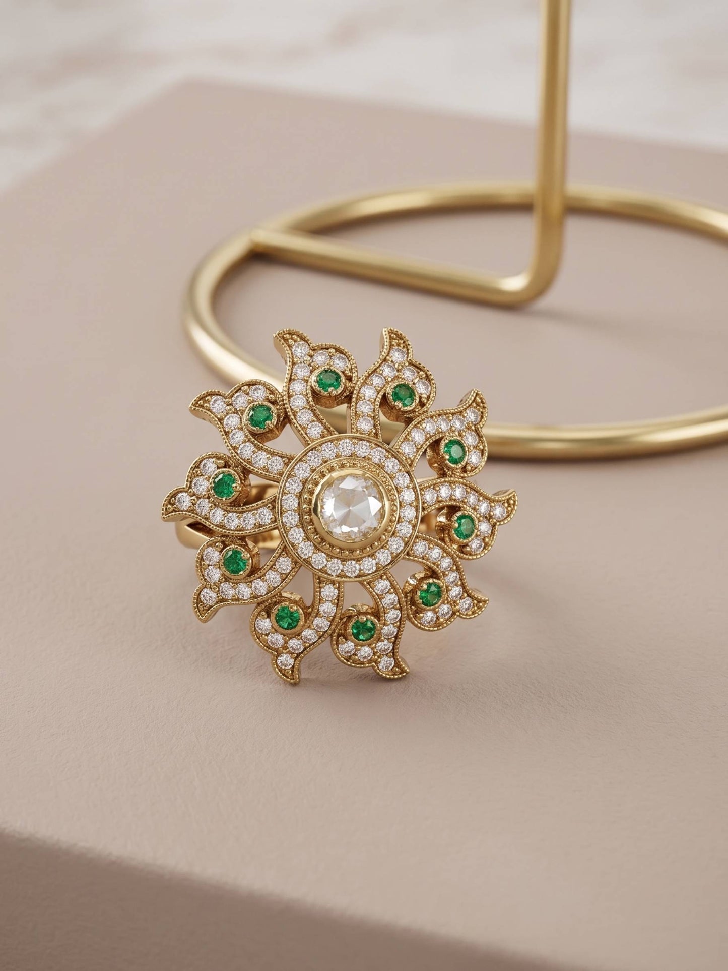 Gold brooch with green gemstones on a beige background