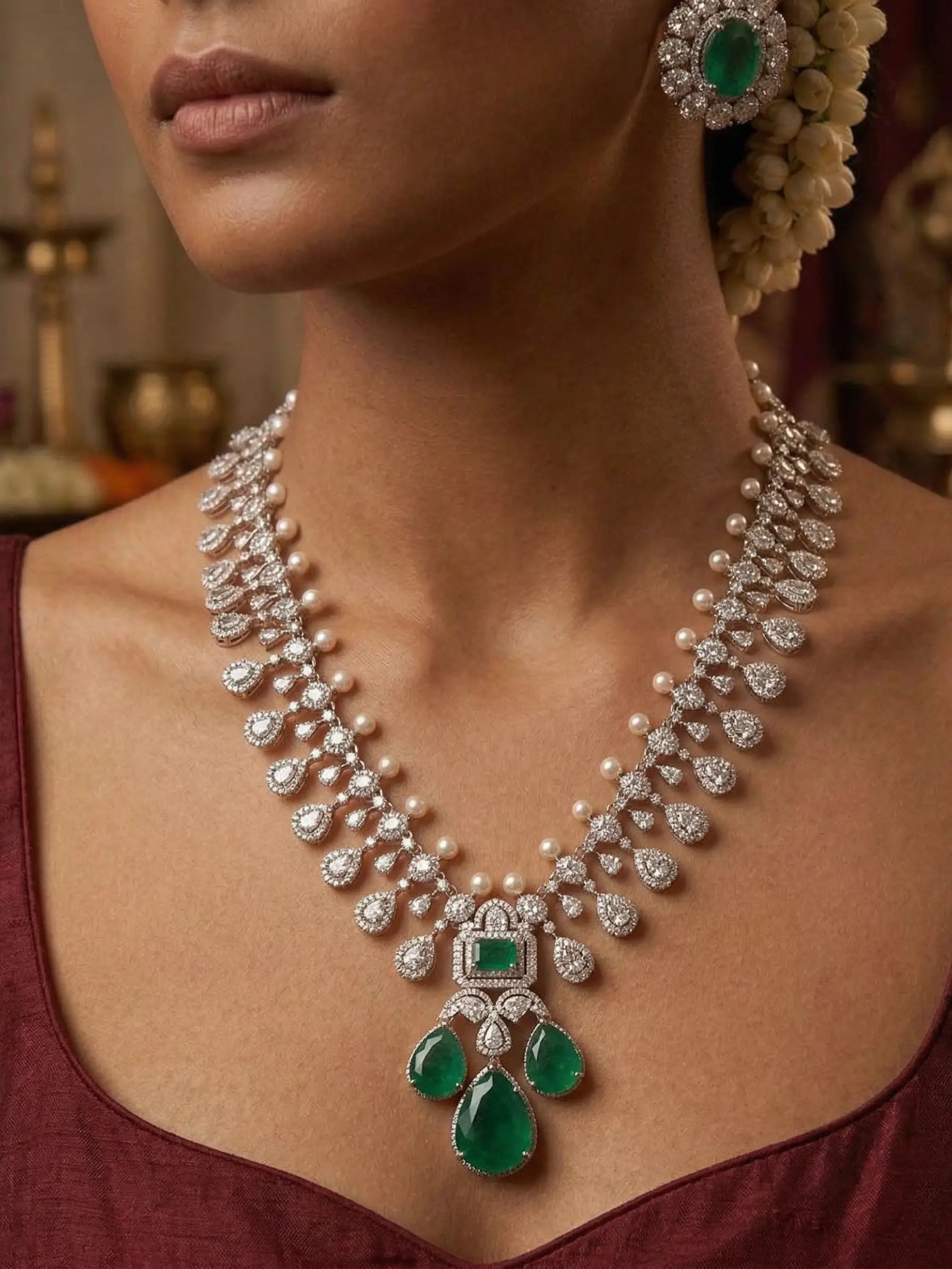 Close-up of a woman wearing an elegant diamond and emerald necklace with a blurred background.