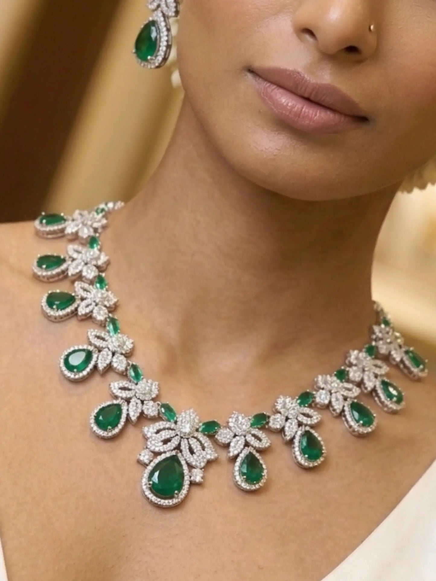 Close-up of a woman wearing a green emerald and diamond necklace and earrings.