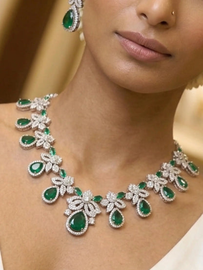 Close-up of a woman wearing a green emerald and diamond necklace and earrings.