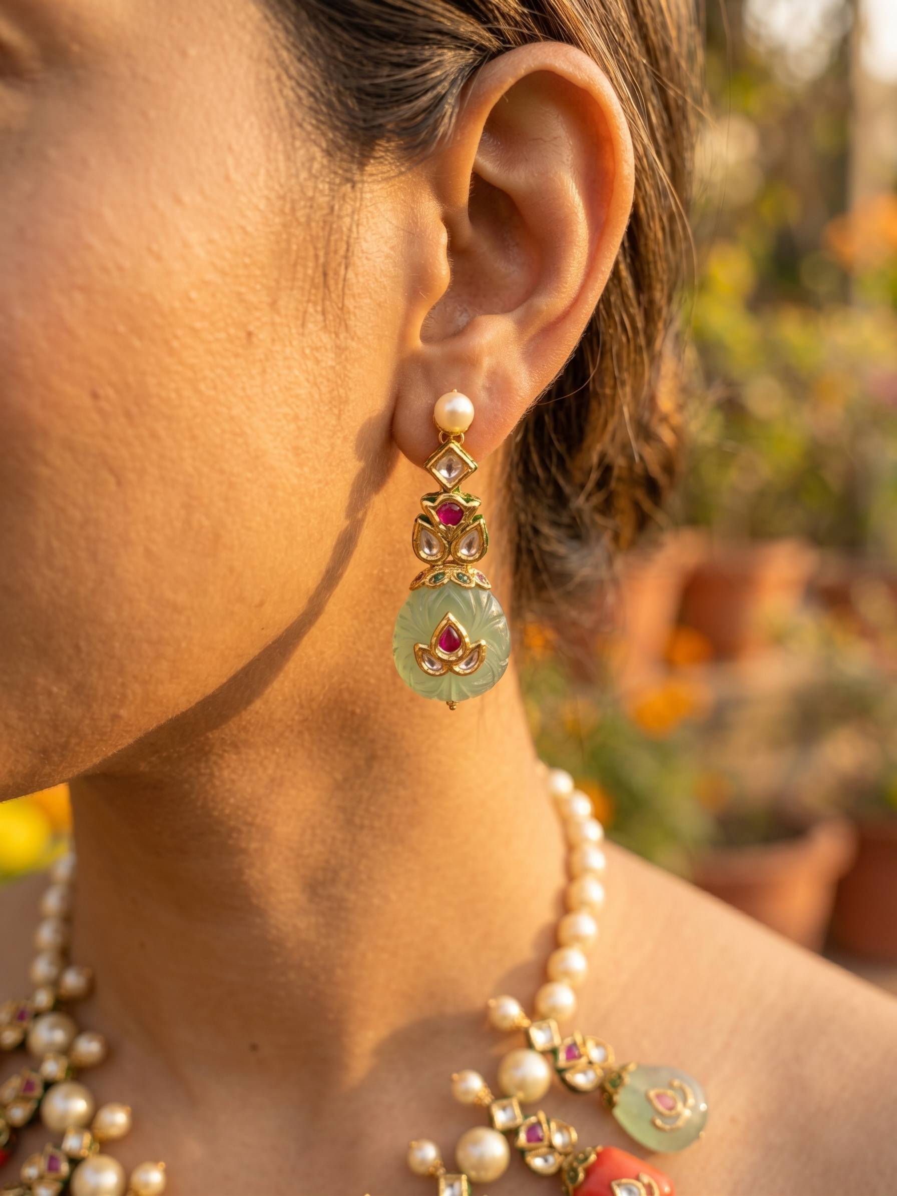 Close-up of an ear wearing a decorative earring with a blurred natural background