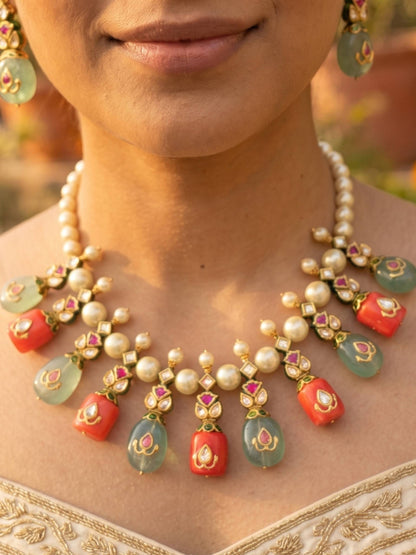 Close-up of a person wearing a detailed necklace with pearls, red stones, and green beads.