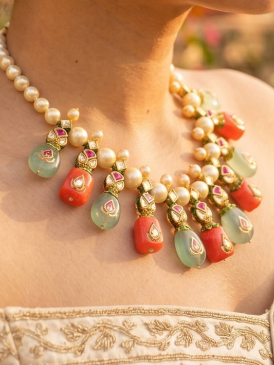 Close-up of a pearl and gemstone necklace on a person wearing a traditional outfit.
