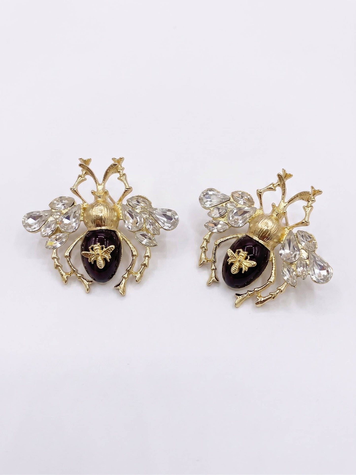 Pair of gold and black insect-shaped earrings on a white background