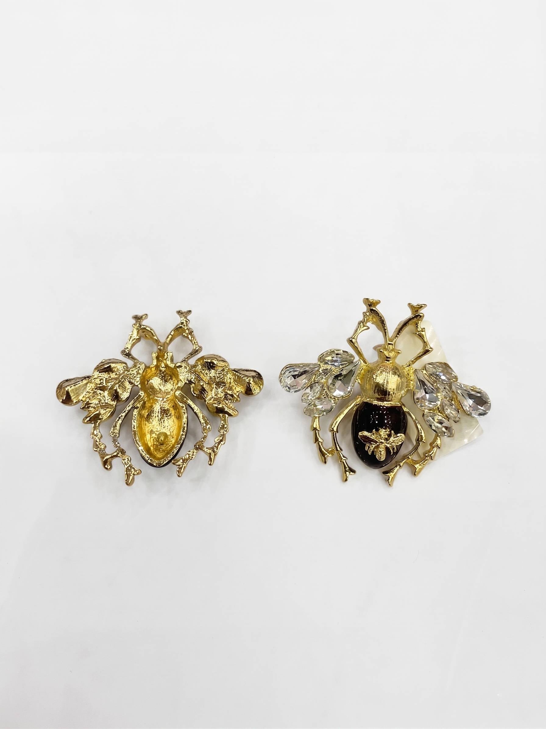 Gold bee-shaped earrings on a light gray background