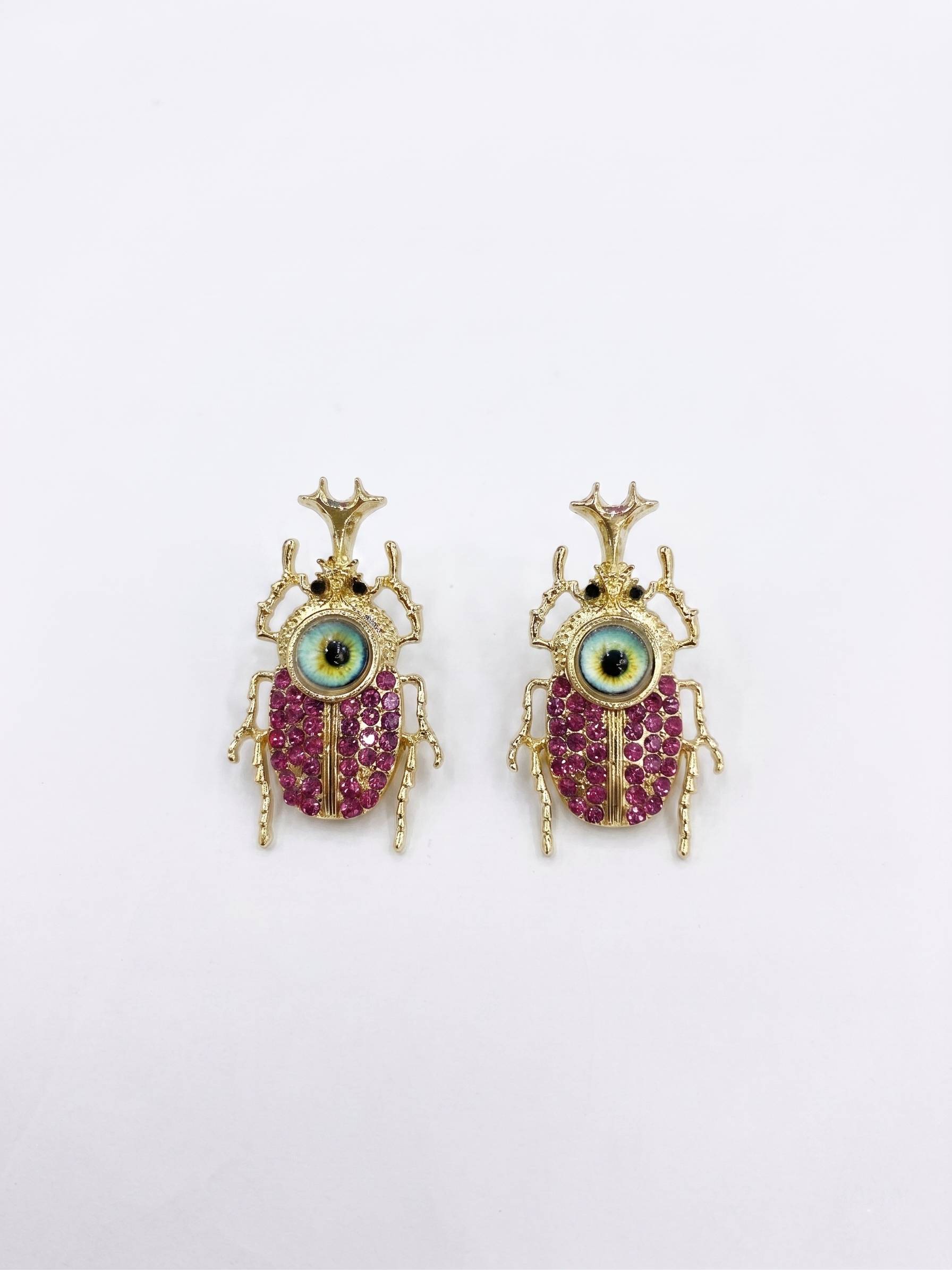 Pair of beetle-shaped earrings with gemstones on a white background