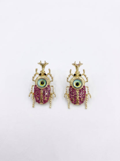 Pair of beetle-shaped earrings with gemstones on a white background