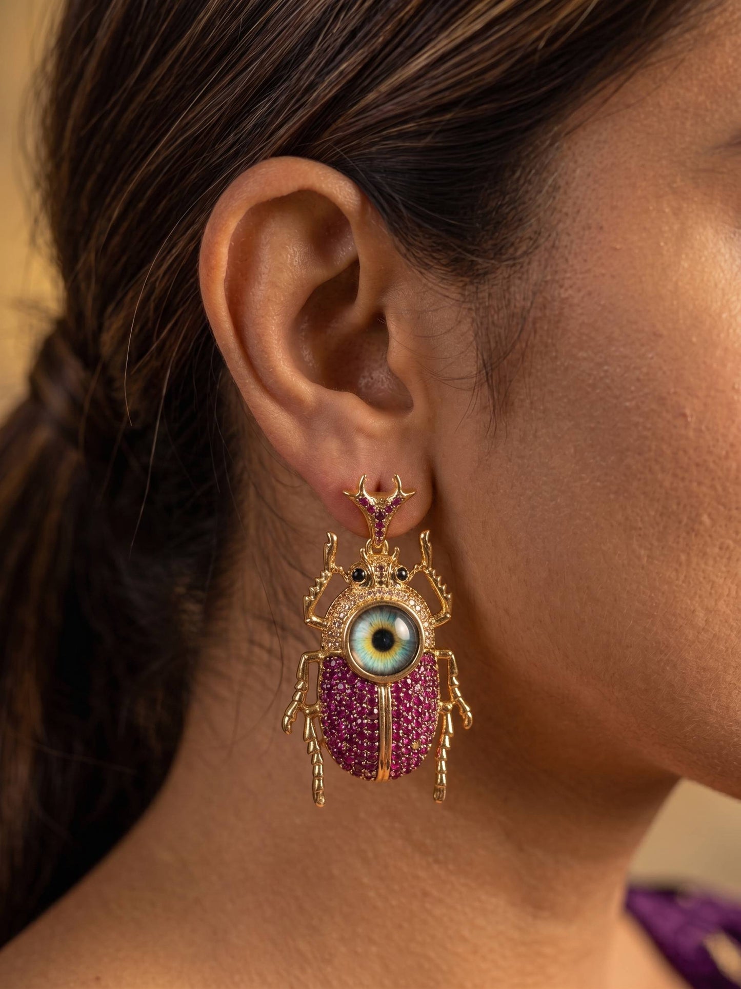 Close-up of an ear wearing a decorative earring with an eye design.