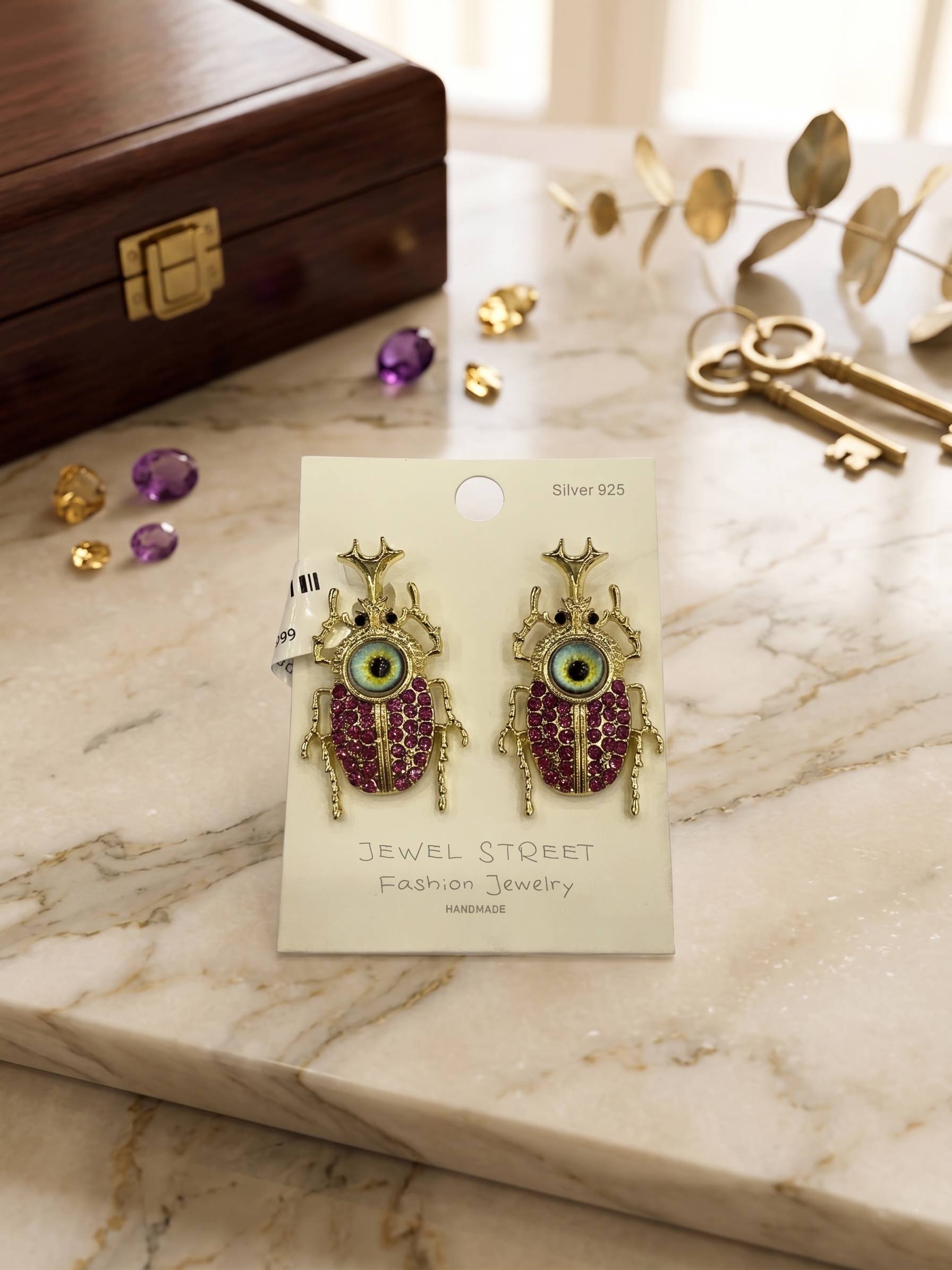 Decorative earrings on a 'Jewel Street' card with a marble surface and jewelry items in the background.