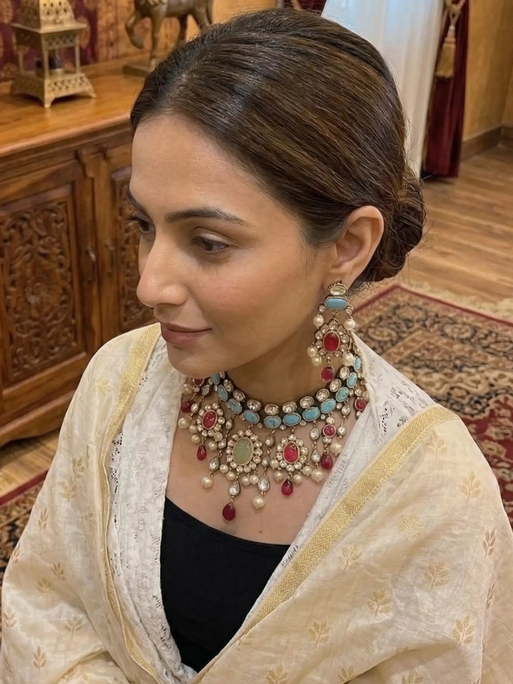 Woman wearing traditional jewelry and a saree in an indoor setting