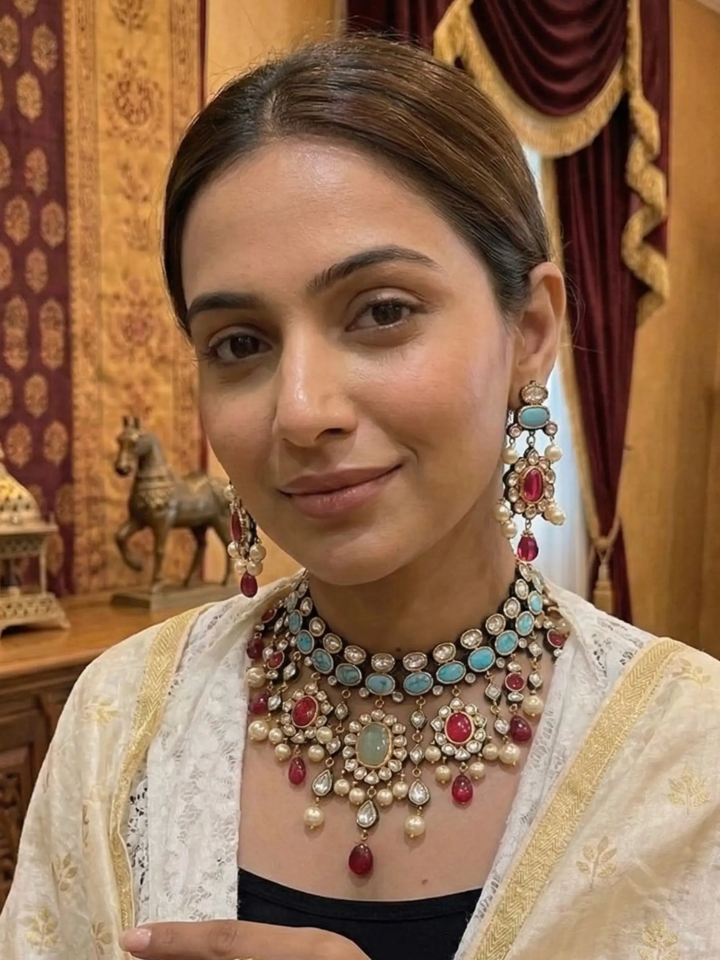 Woman wearing elaborate jewelry in an ornate indoor setting