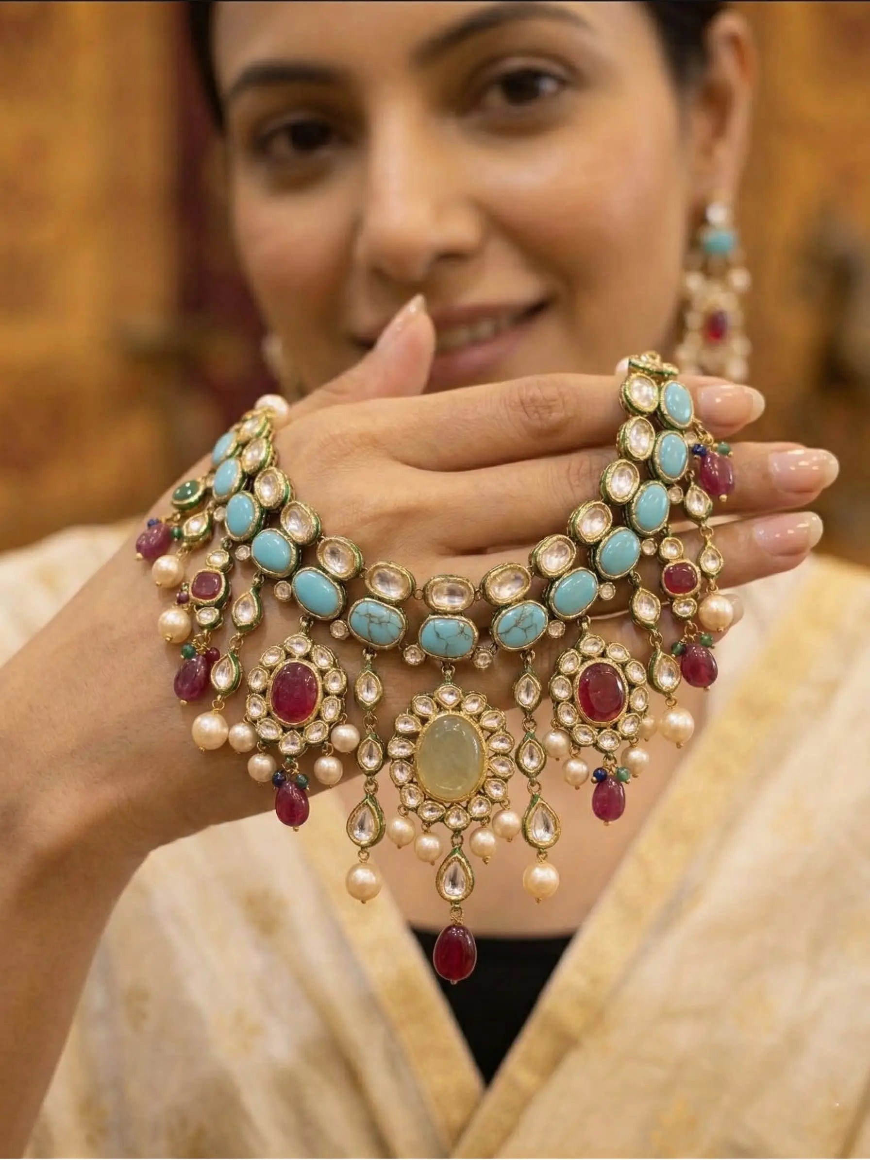 Woman wearing a traditional necklace with pearls, turquoise stones, and red gemstones.