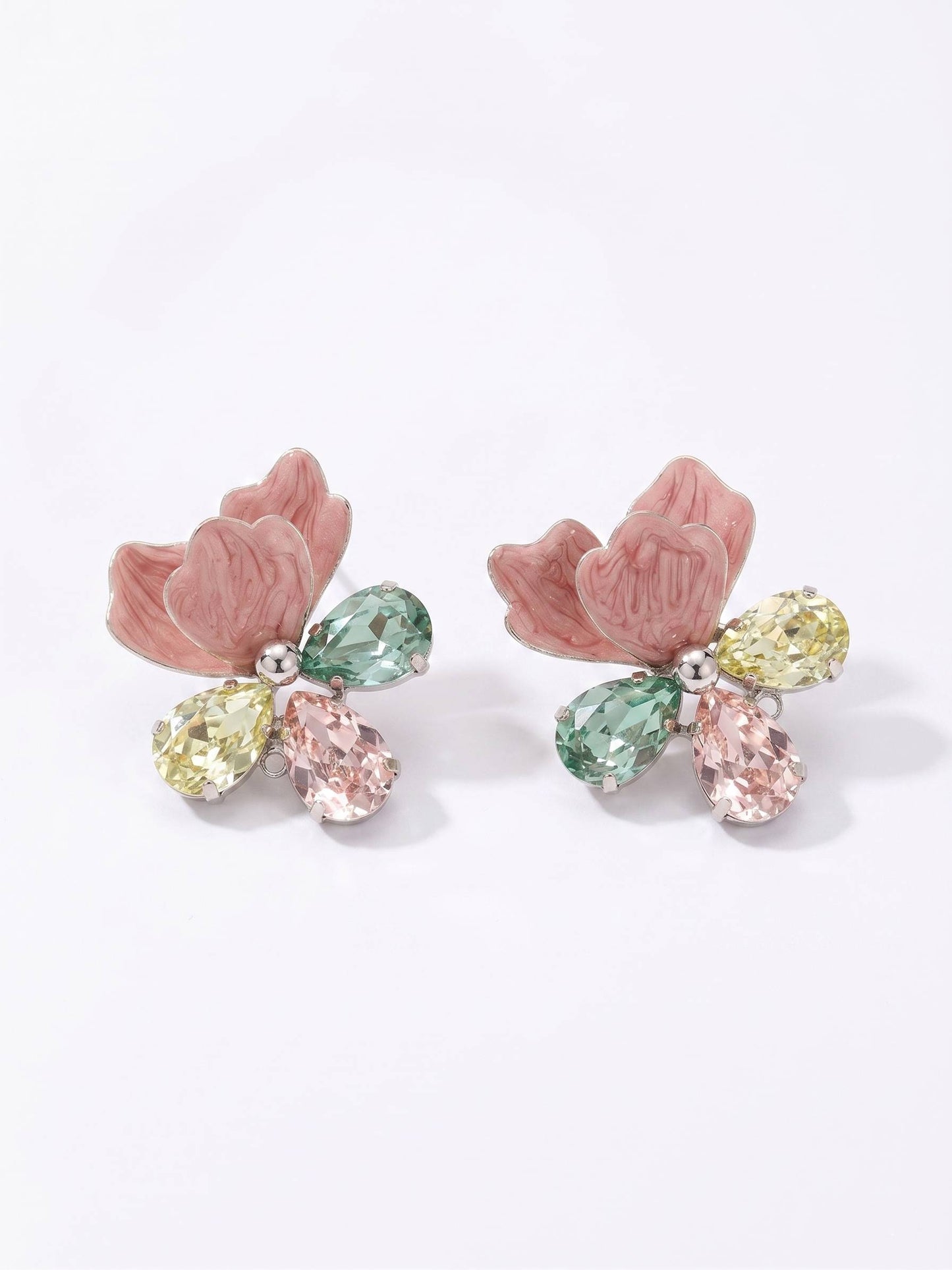 Pair of earrings with pink floral designs and multicolored gemstones on a white background