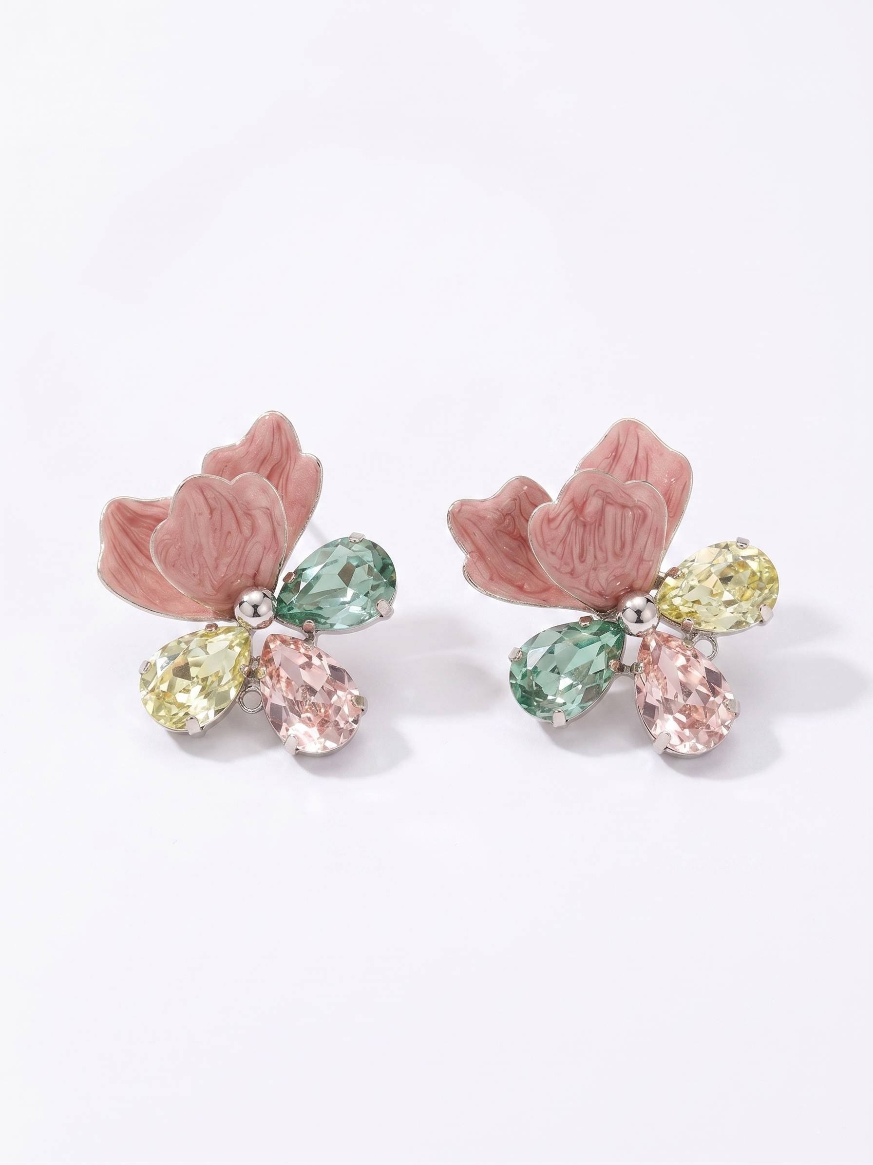 Pair of earrings with pink floral designs and multicolored gemstones on a white background