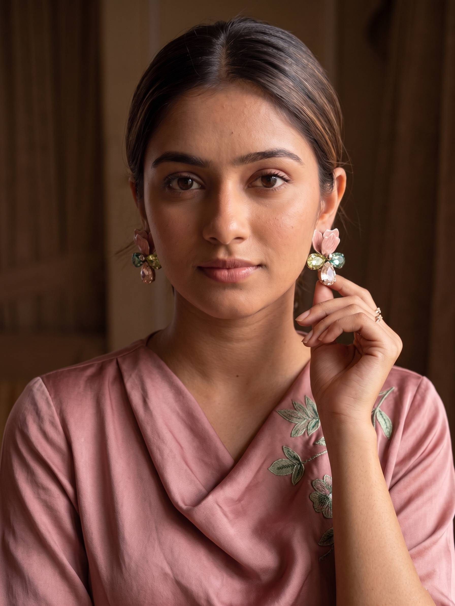 Woman wearing a pink saree with floral patterns, posing indoors.