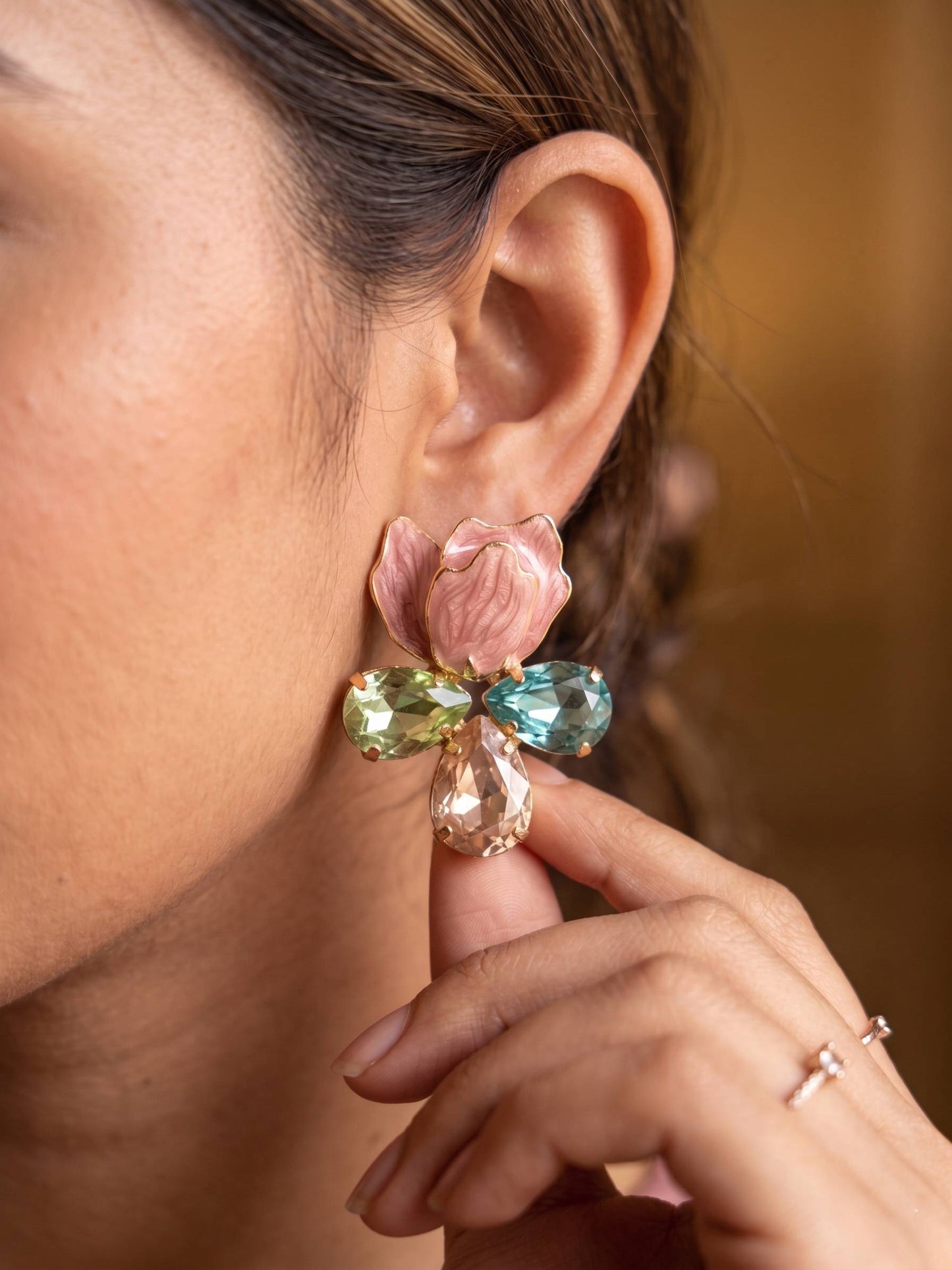 Close-up of a person wearing a colorful floral earring with a blurred background