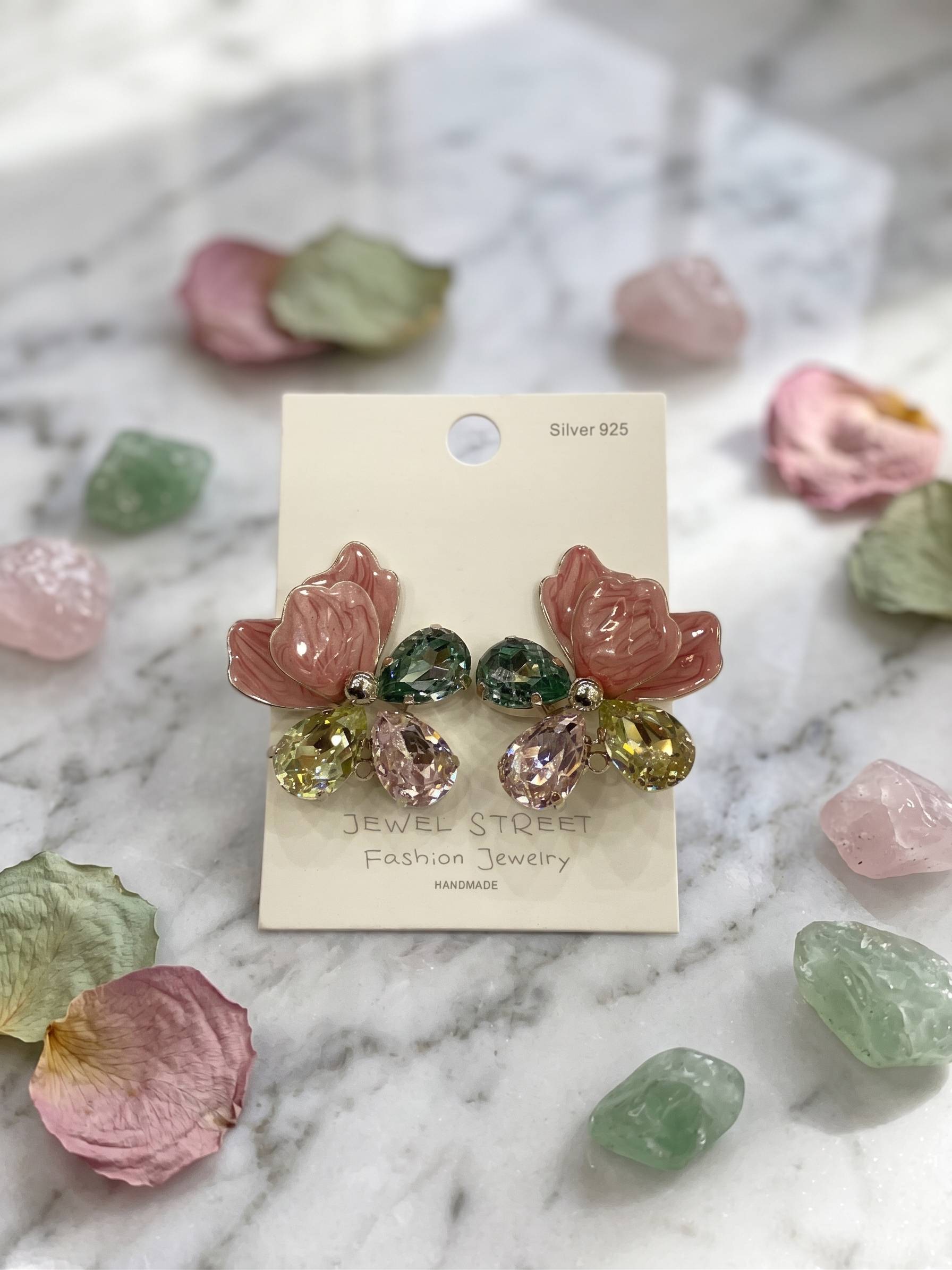 Colorful gemstone earrings on a 'Jewel Street' branded card against a marble background.