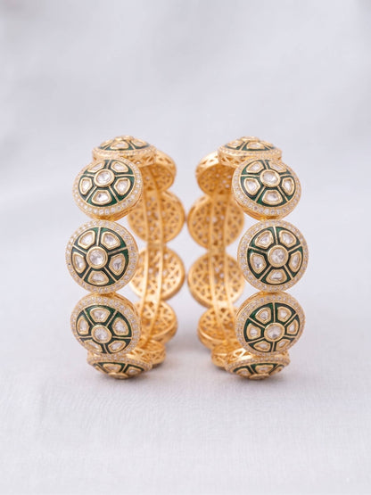 Pair of gold and green earrings on a light gray background