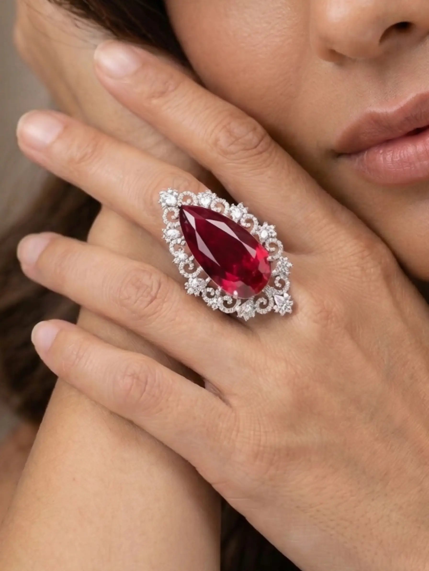 A woman’s hand wearing an oversized red fashion ring, highlighting its royal design and craftsmanship