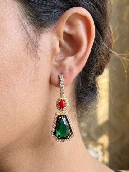 Close-up of an ear wearing a green and red gemstone earring with a blurred background