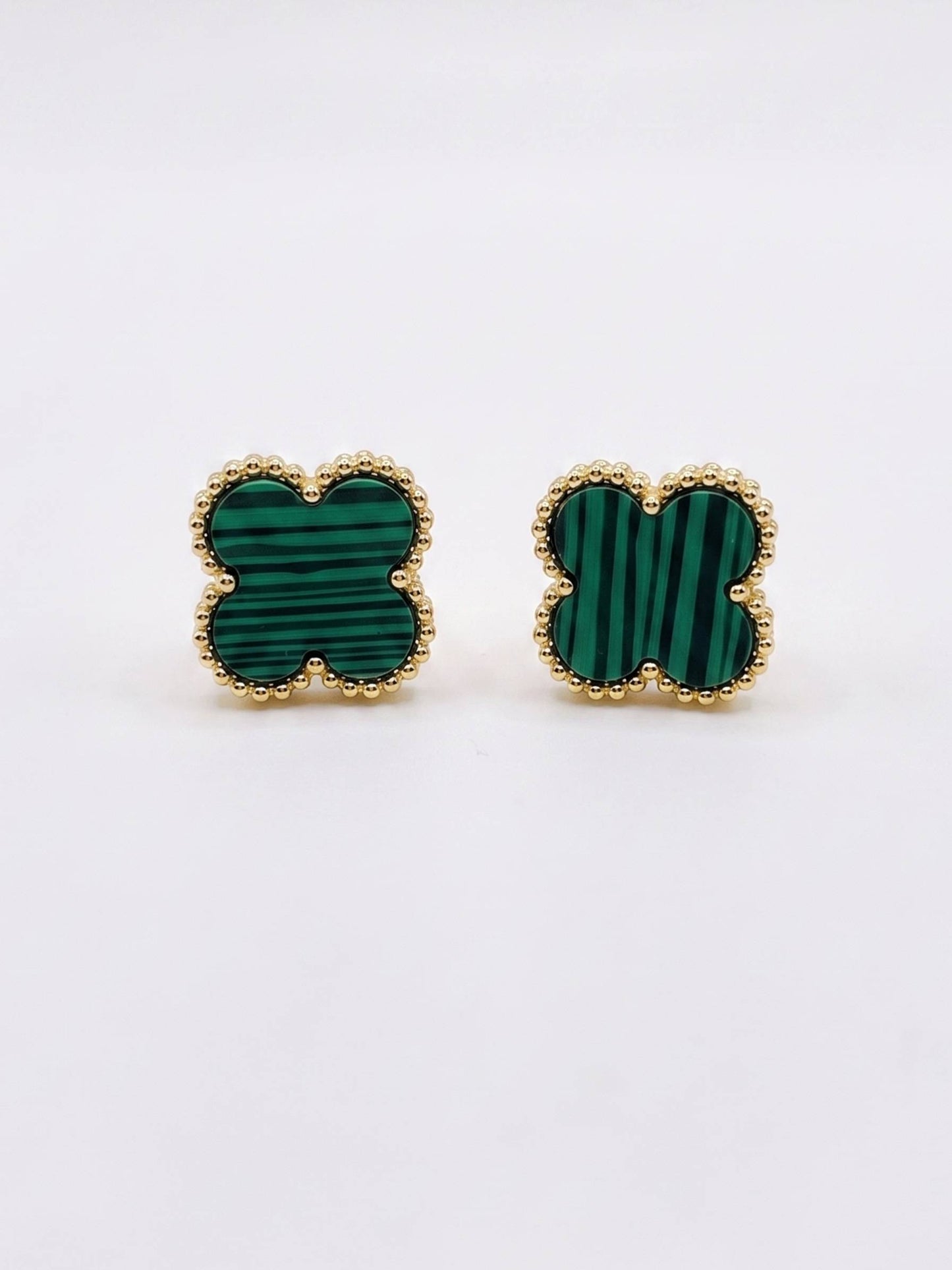 Pair of green clover-shaped earrings with gold frames on a white background