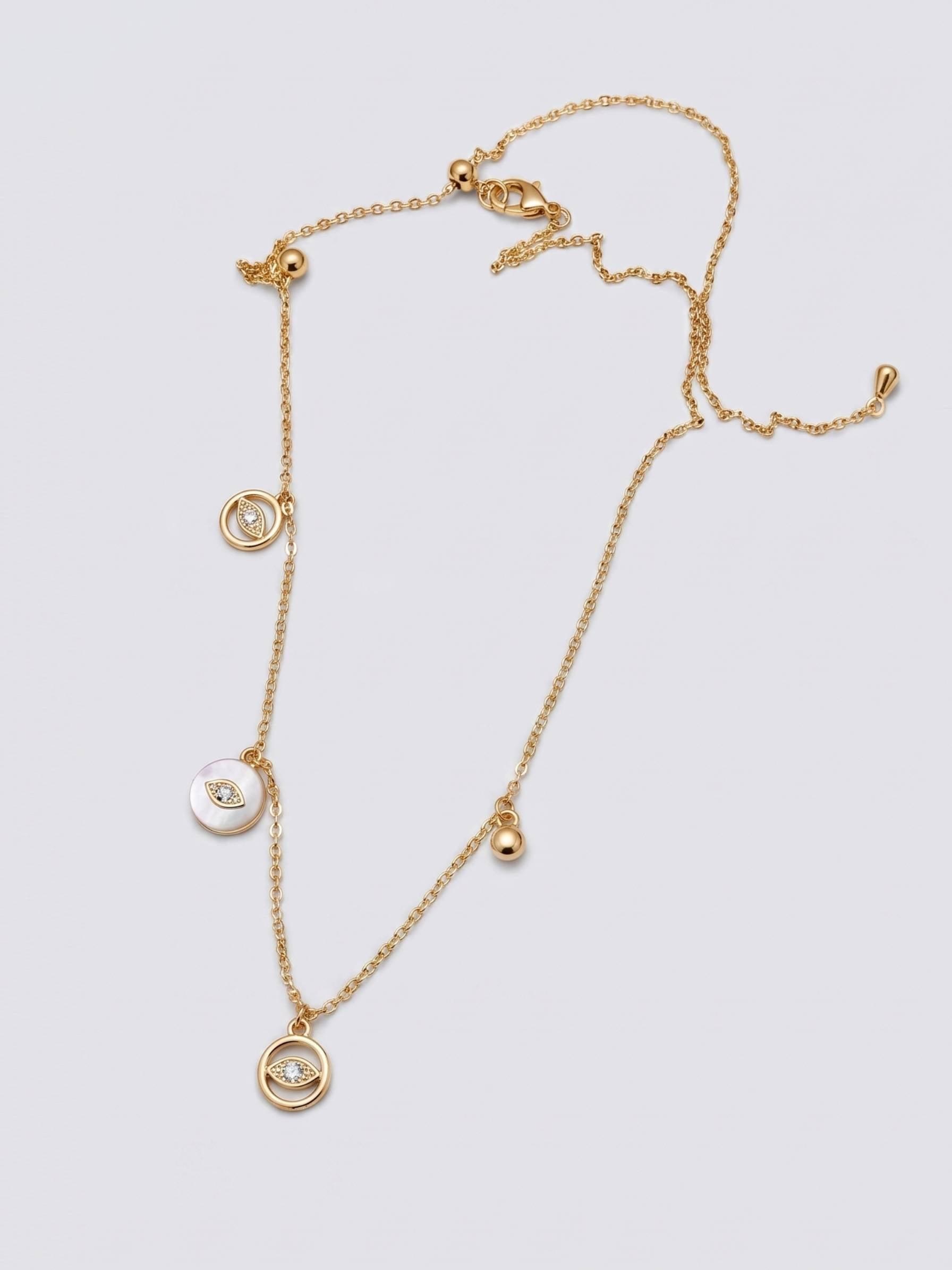 Gold necklace with three circular pendants on a light gray background