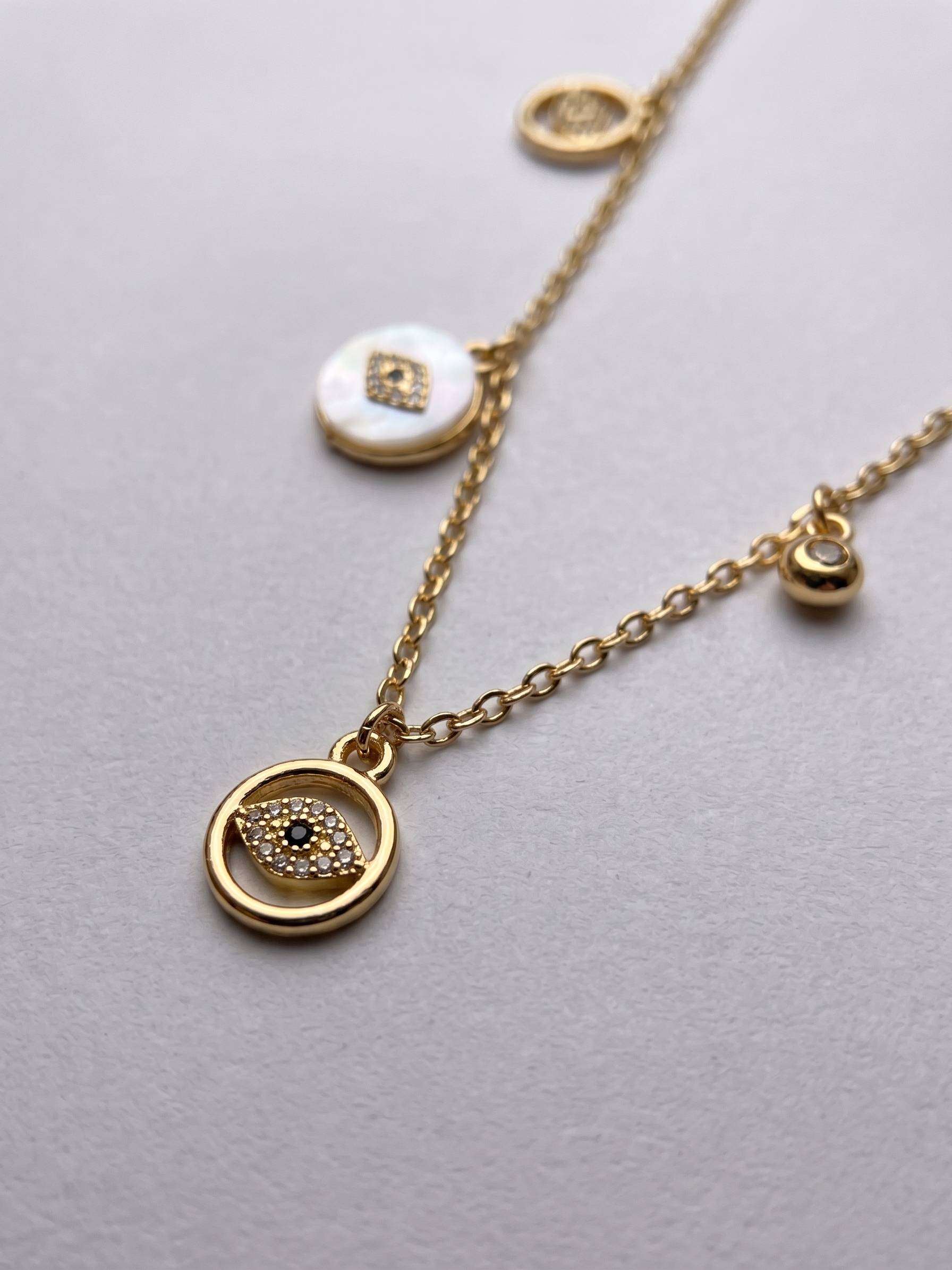 Gold necklace with circular pendants on a light gray background