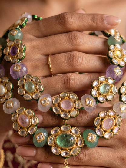 Close-up of hands wearing intricately designed gold jewelry with gemstones.