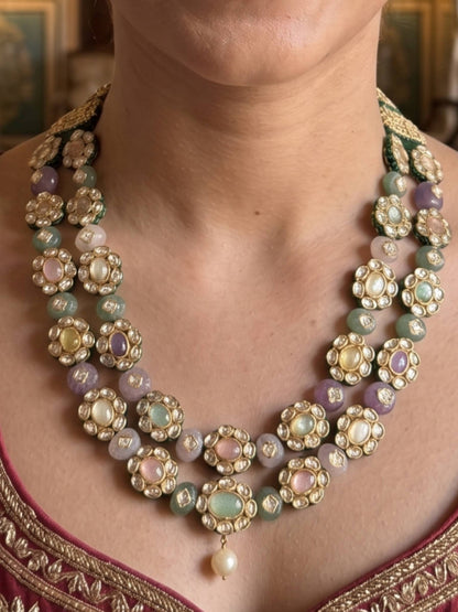 Close-up of a person wearing a decorative necklace with pastel stones and gold accents.