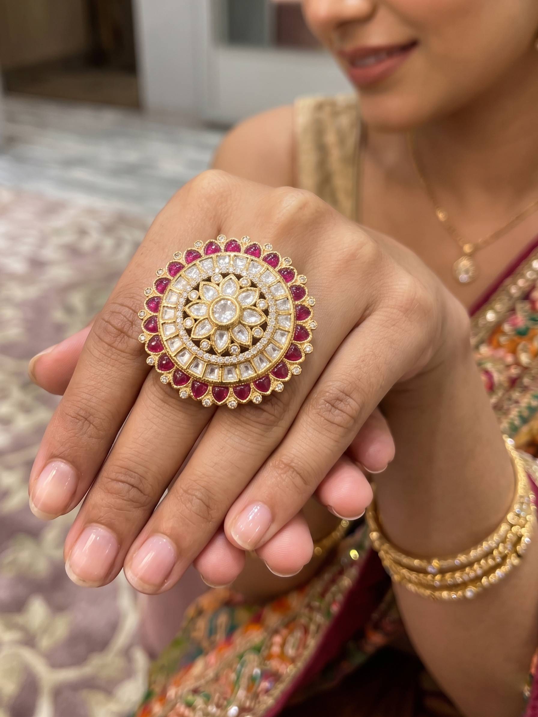 Close-up of a hand wearing a decorative ring with red stones and gold accents.