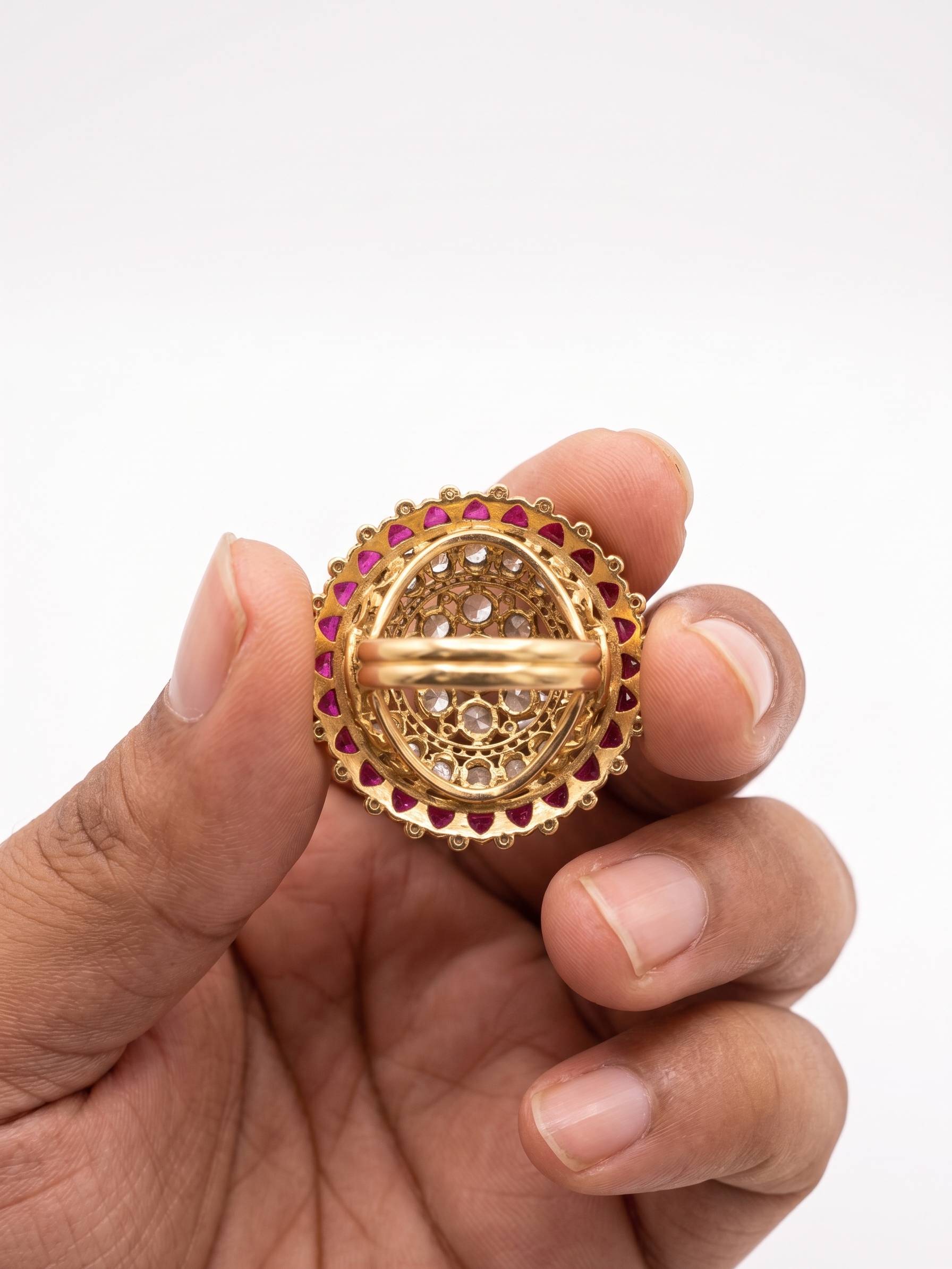 Gold ring with gemstones held in a hand against a white background