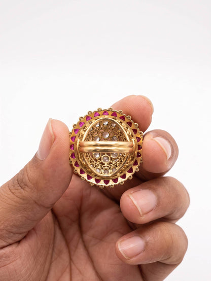 Gold ring with gemstones held in a hand against a white background
