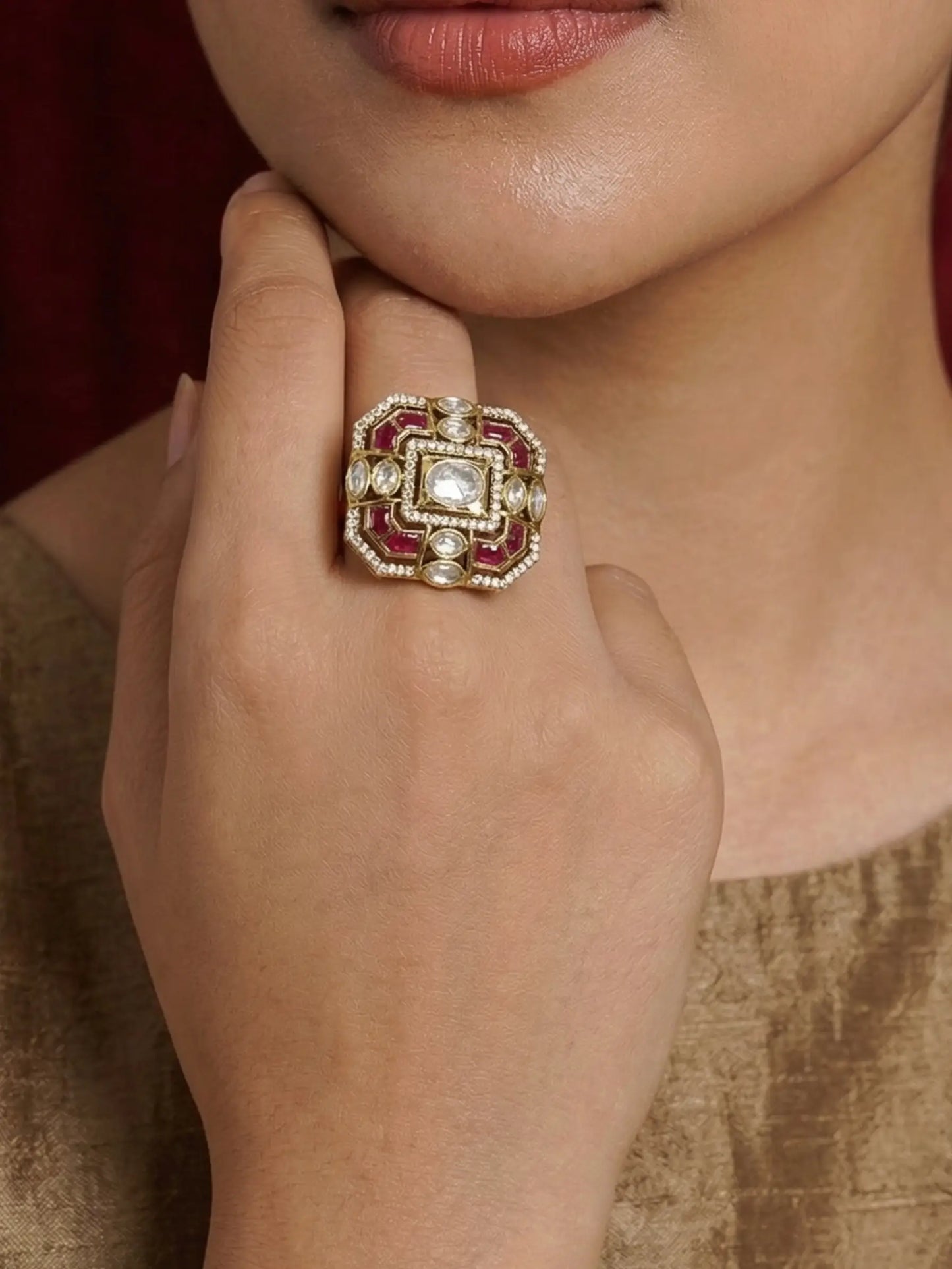 Close-up of a hand wearing an ornate ring with a diamond and ruby stones.