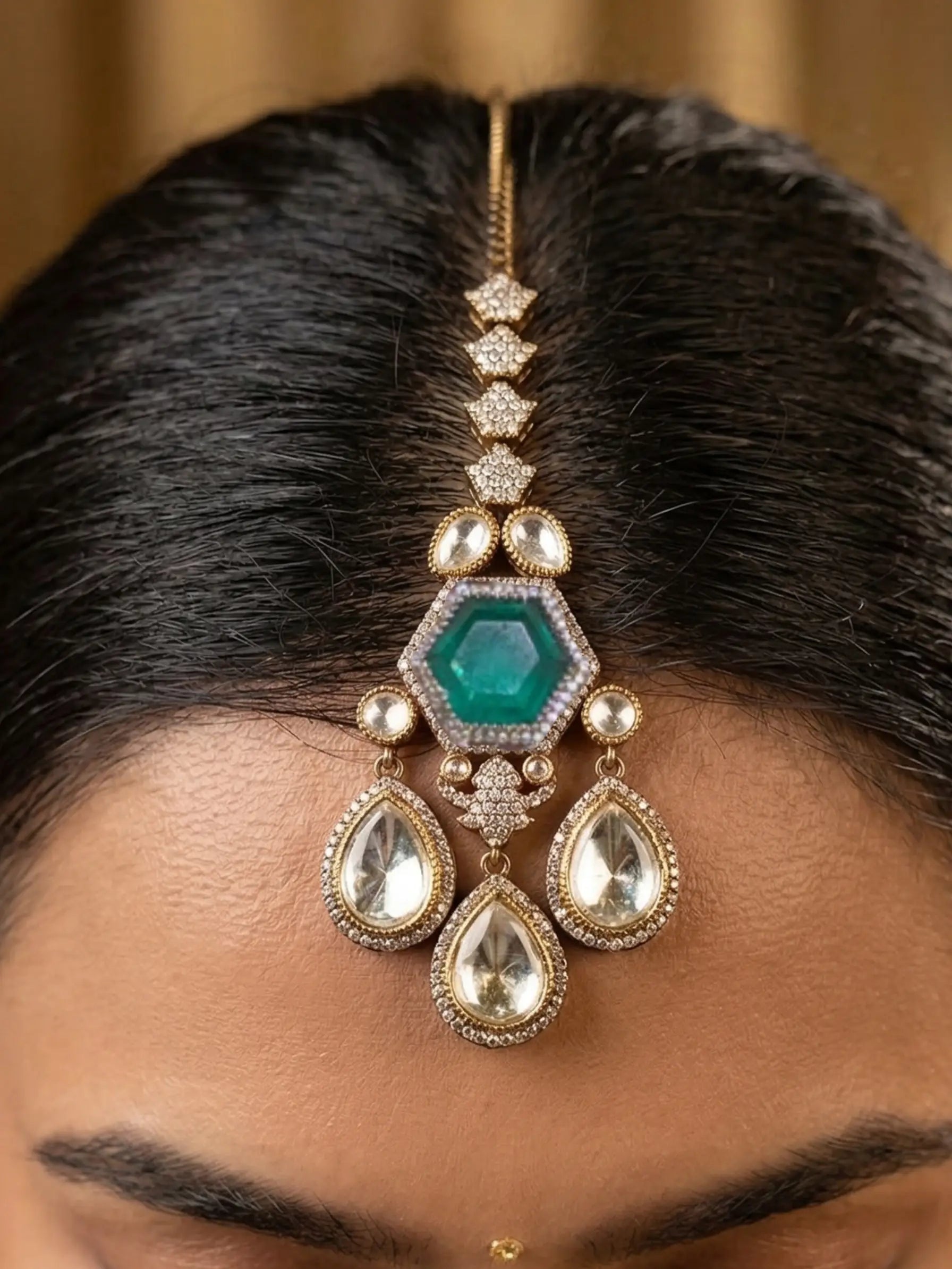 Close-up of a person wearing a decorative hairpiece with green gemstone and gold accents.