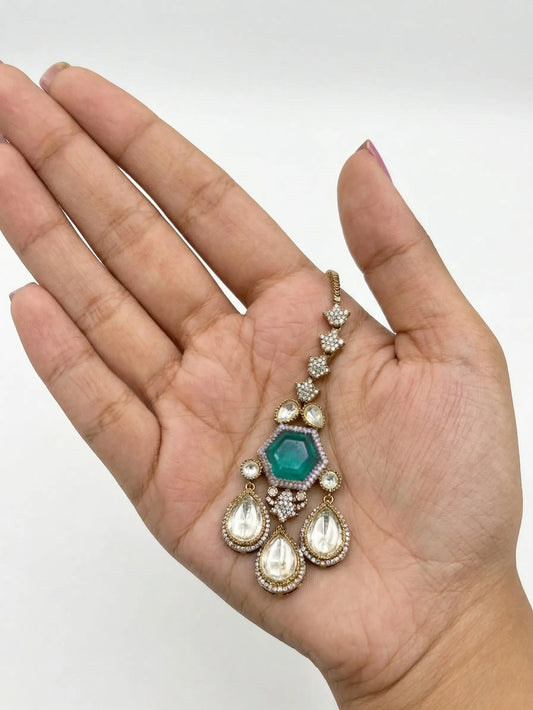 Jewelry with a green gemstone held in a hand against a white background