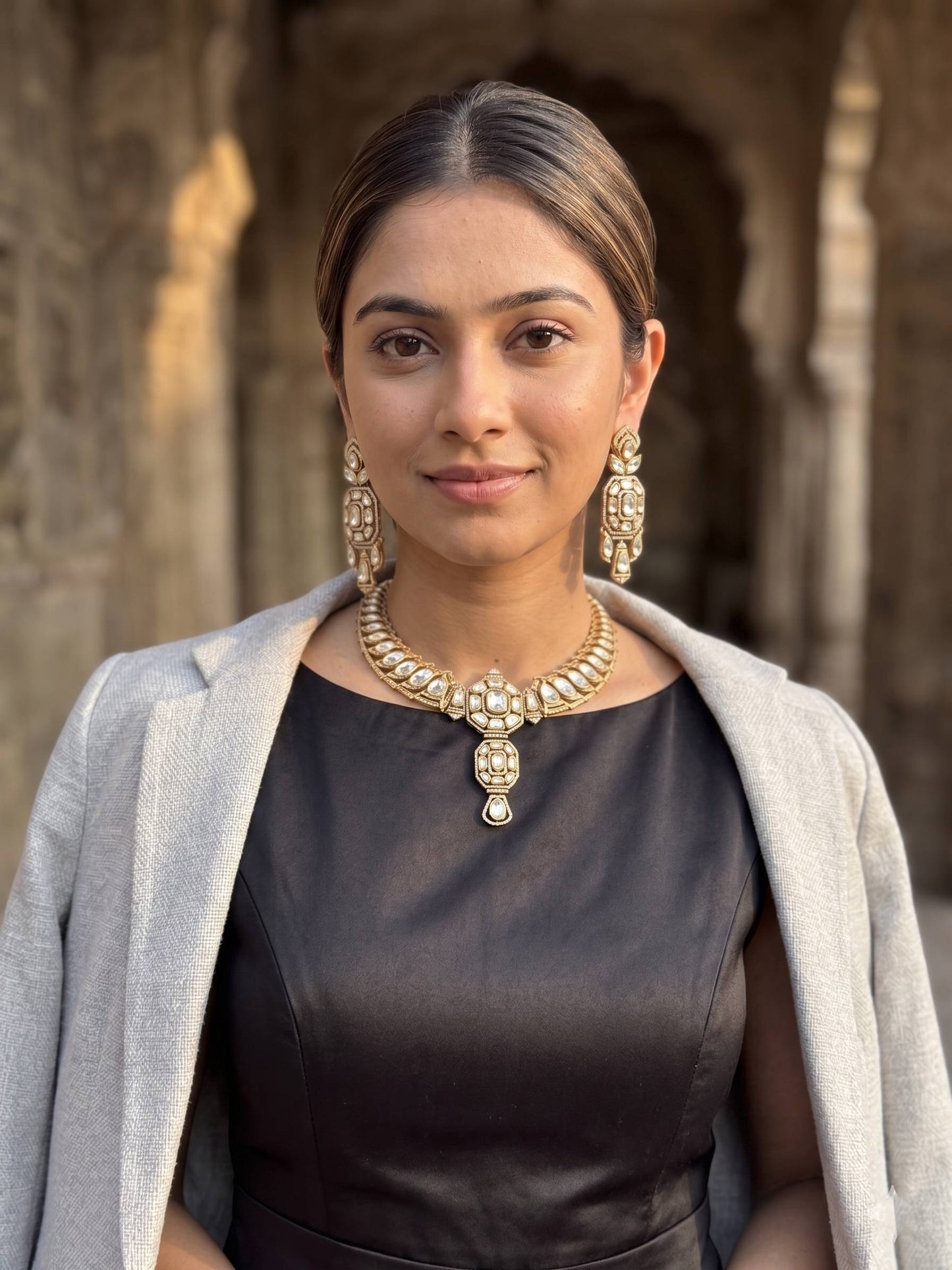 Woman wearing gold jewelry in front of an architectural background
