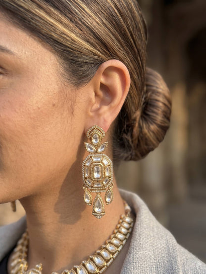 Close-up of a person wearing gold earrings and a necklace with a blurred background