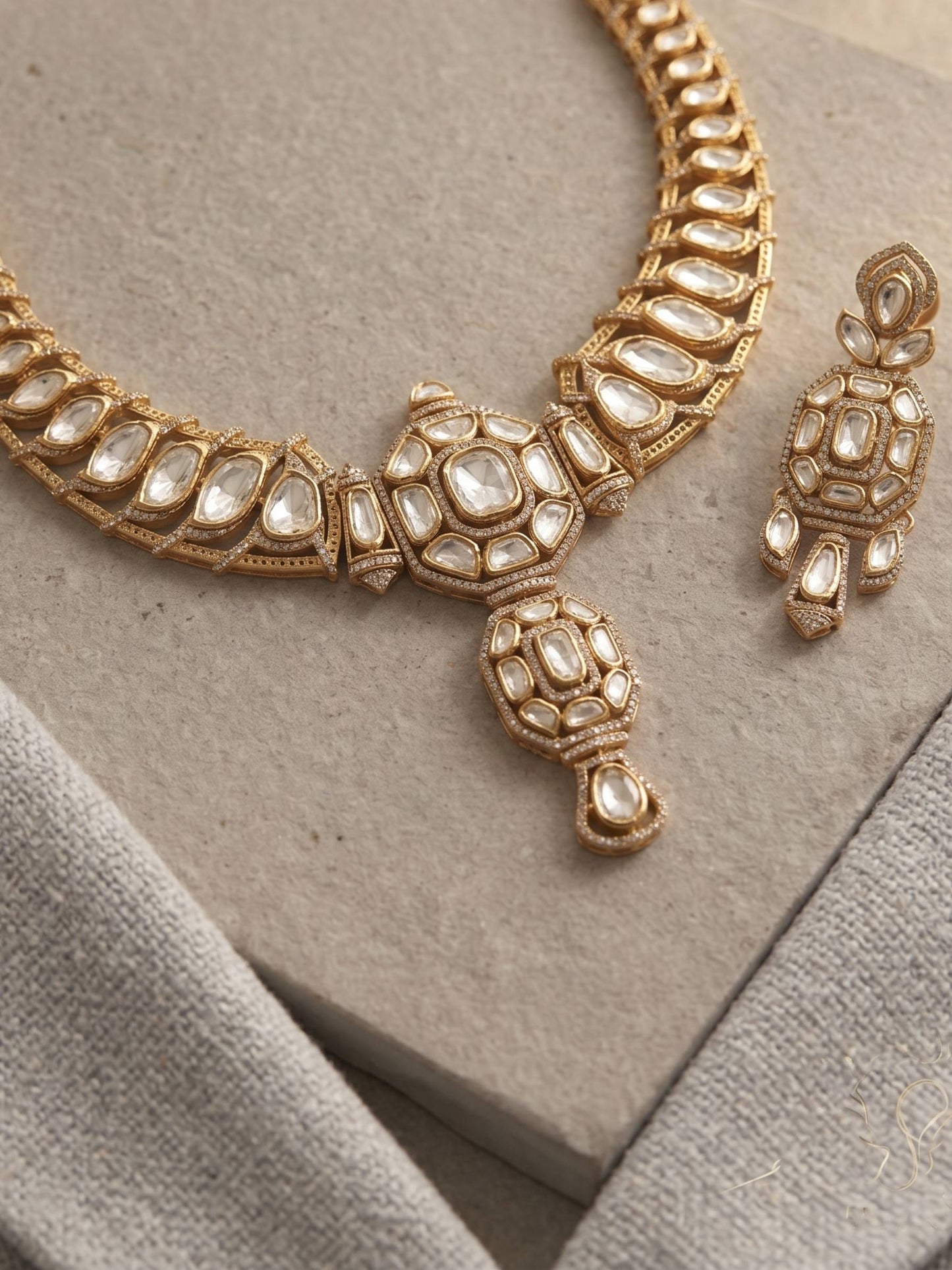 Gold necklace and earrings on a textured surface