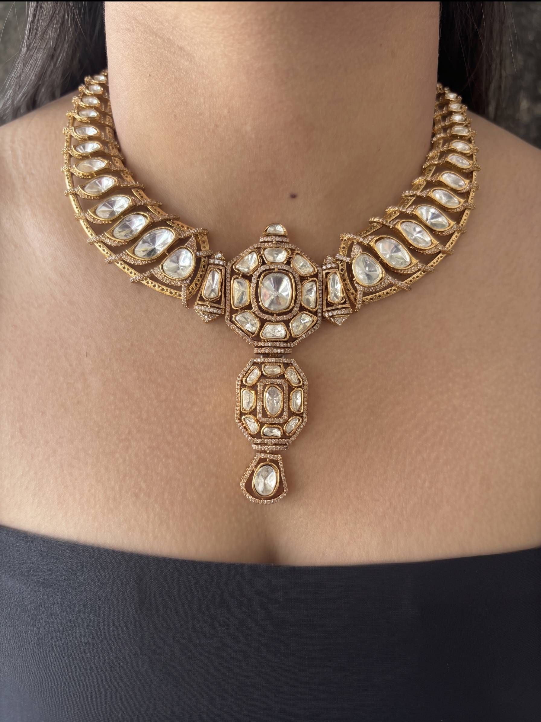 Gold necklace with intricate design worn by a person