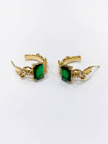 Gold earrings with green gemstones on a white background
