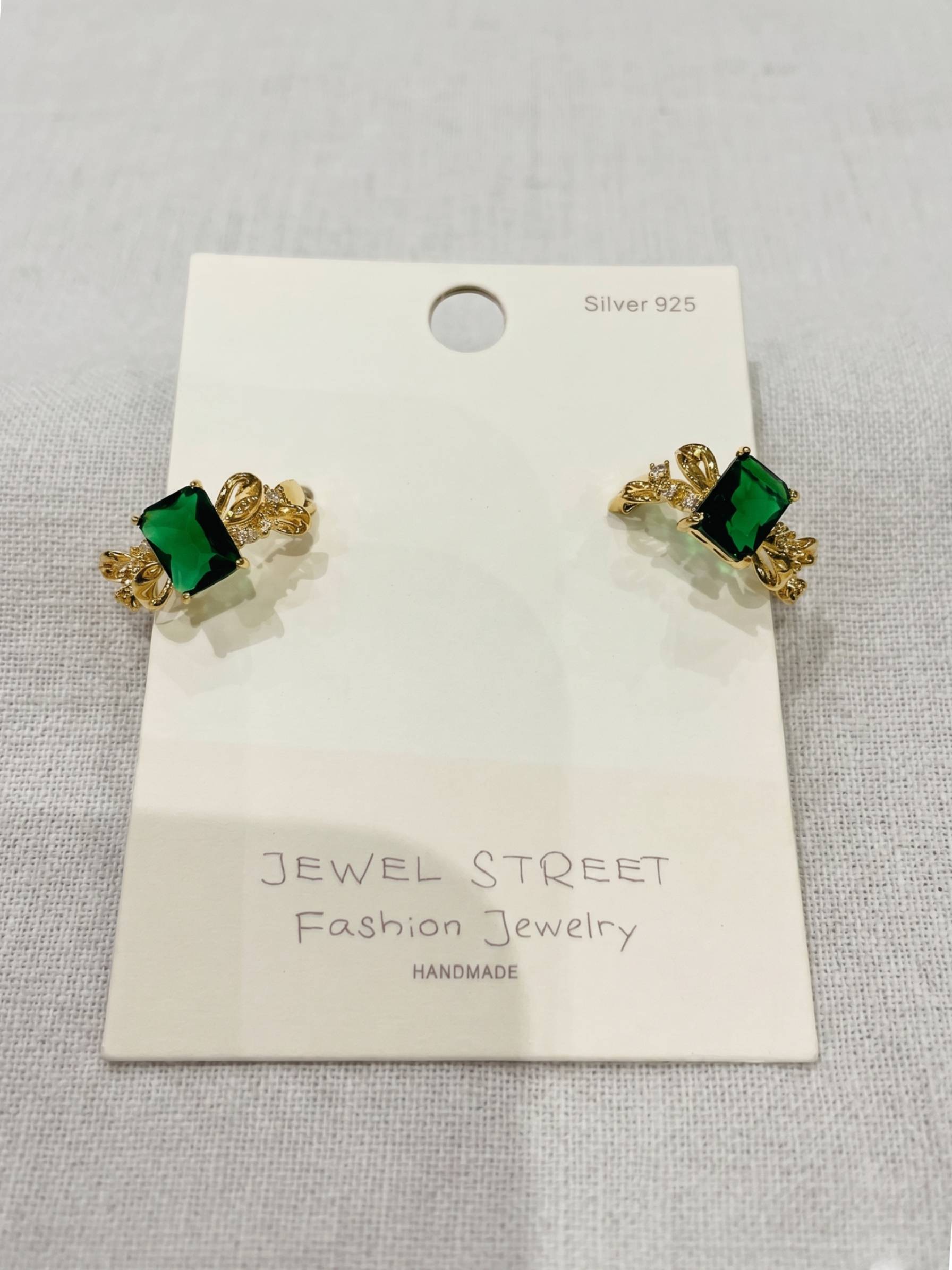 Gold and green earrings on a Jewel Street branded card.