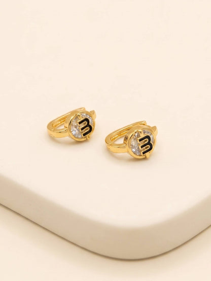 Gold rings with letter 'M' on a beige surface
