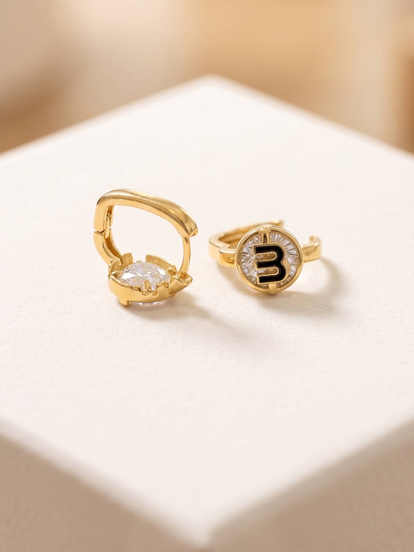 Gold hoop earrings with a central gemstone on a light background