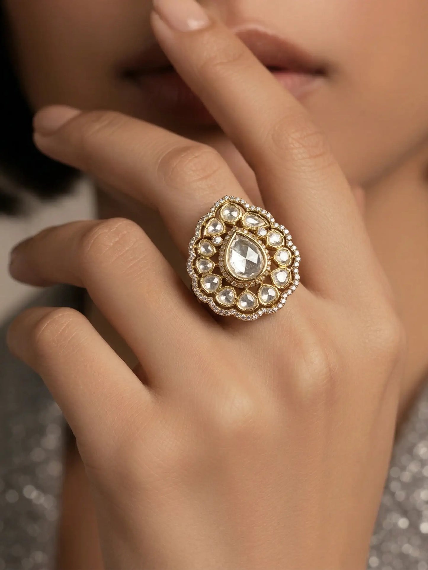 Close-up of a handcrafted Polki Ring for women on a female hand, featuring a pear-shaped center stone and intricate floral design.