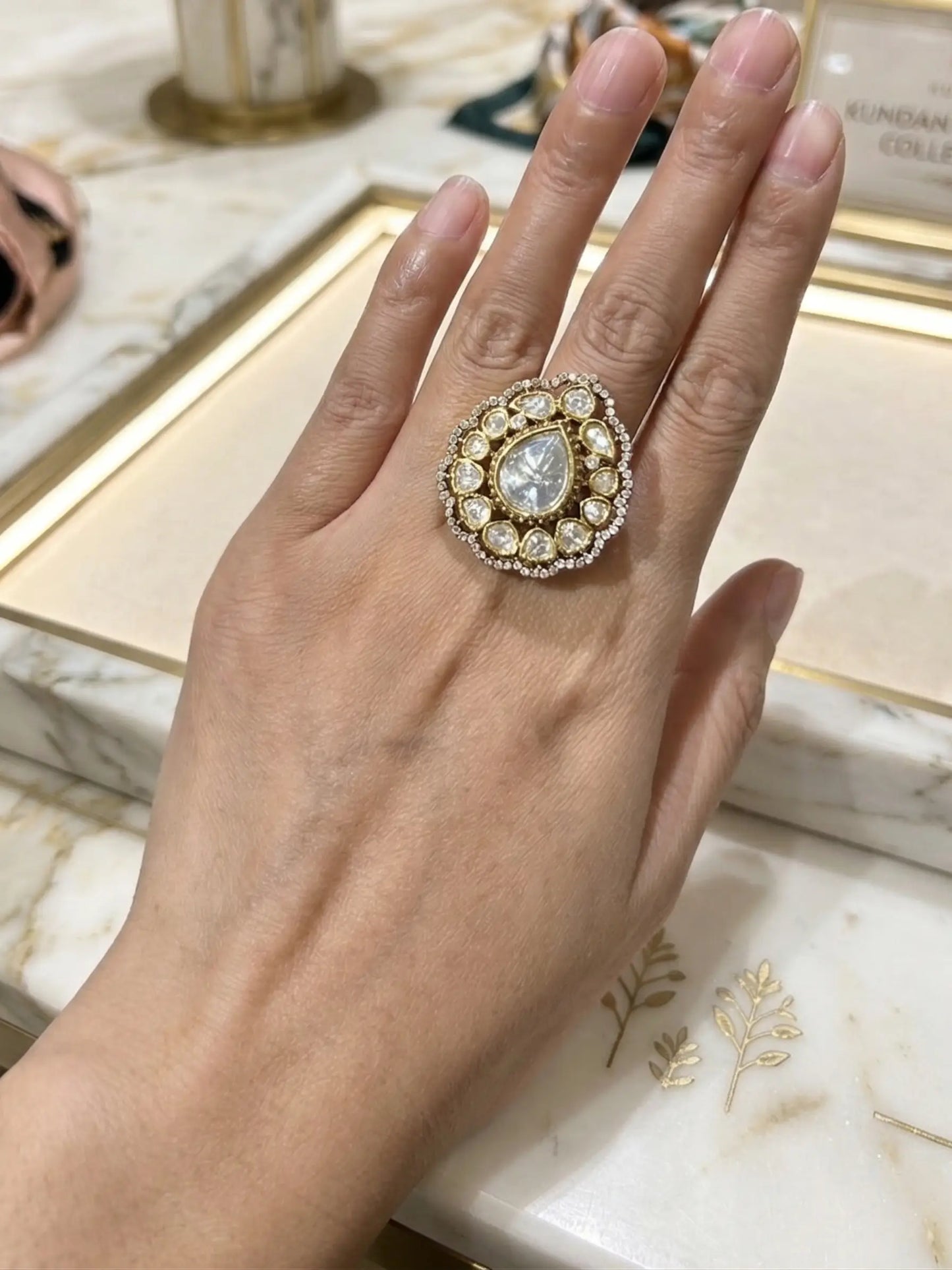 Hand wearing a decorative ring on a marble surface